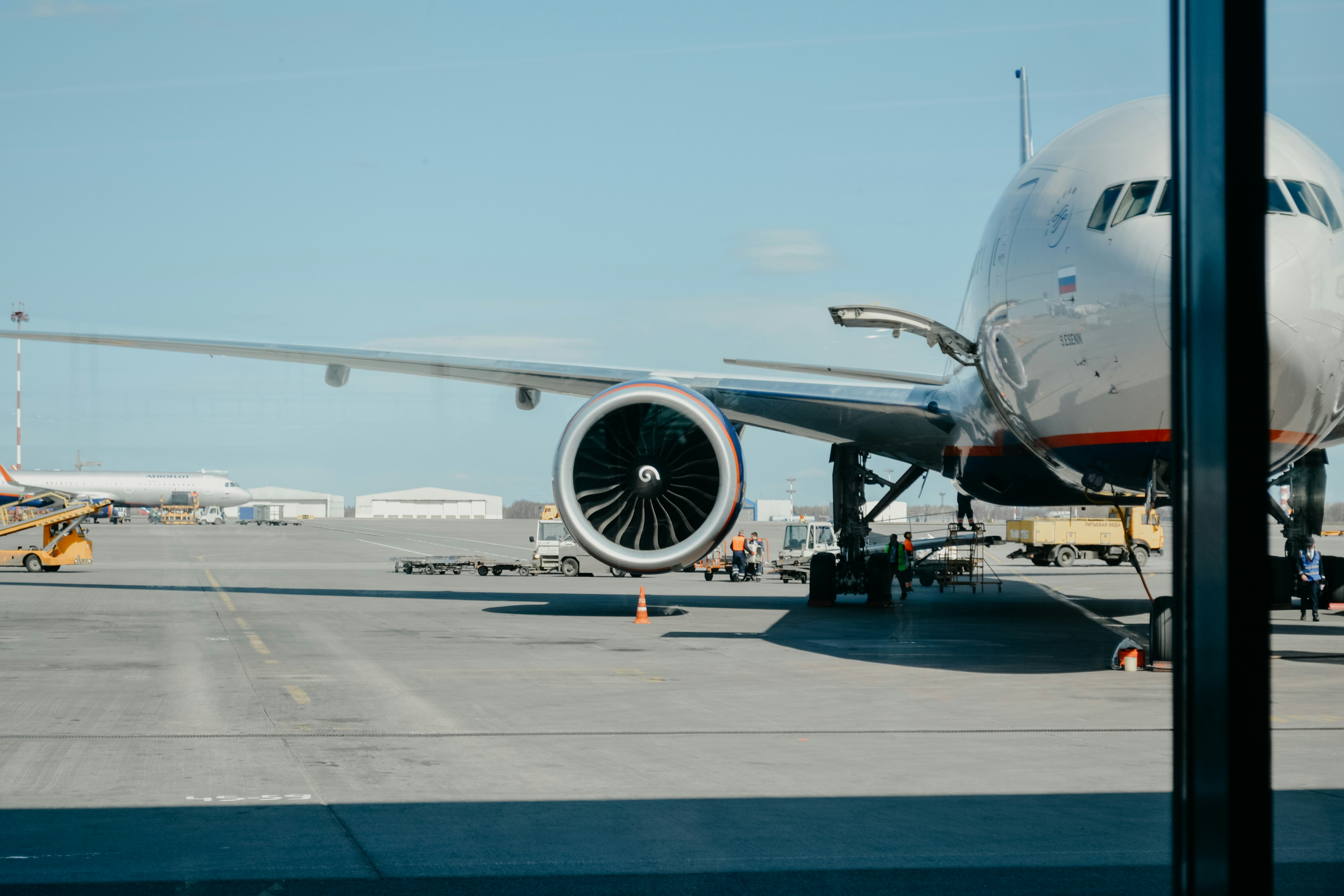 Baggage tow tractors operating beside an aircraft on the airport apron during ground handling.